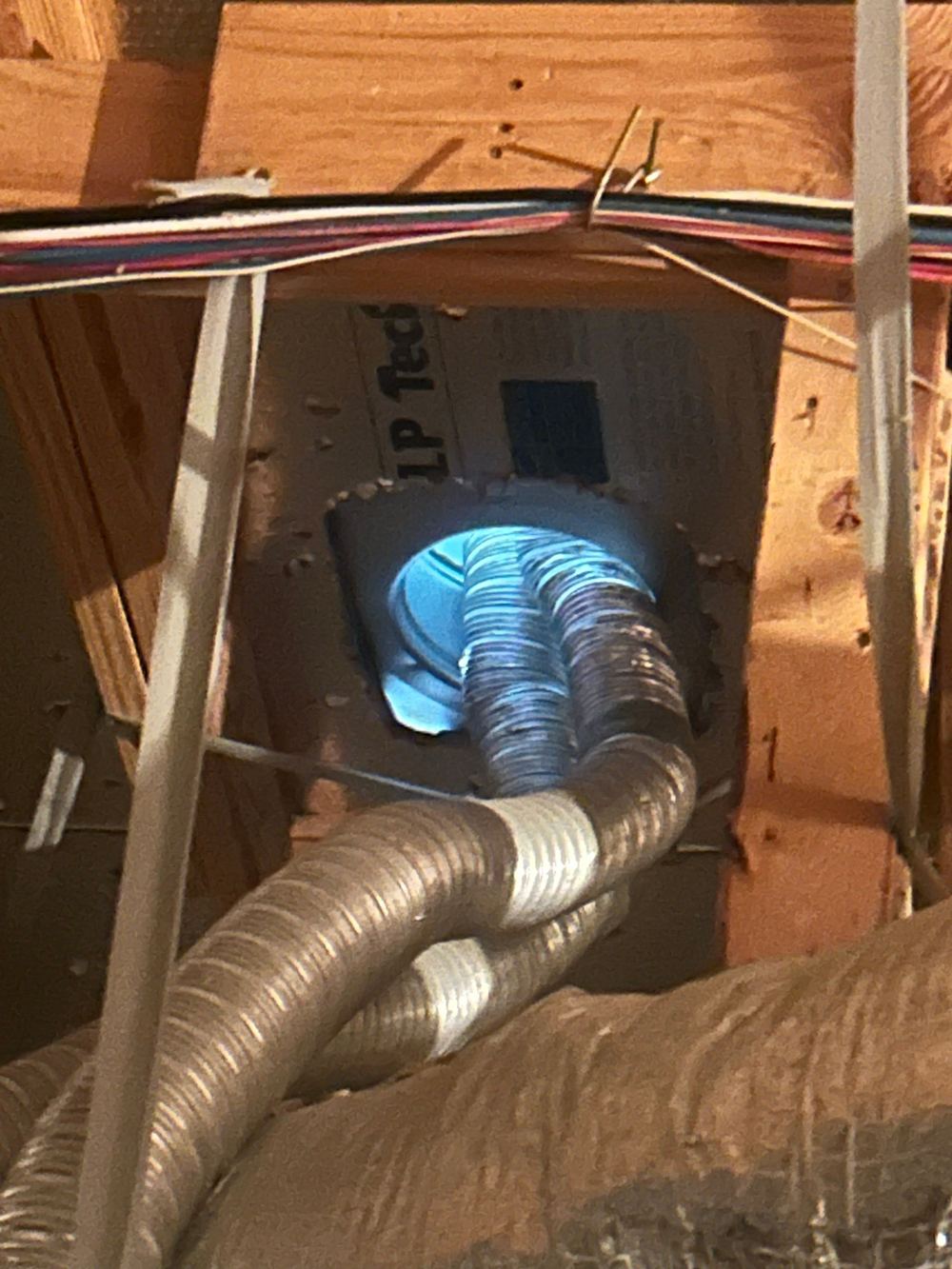 Attic ventilation ductwork and insulation inside a Houston area attic