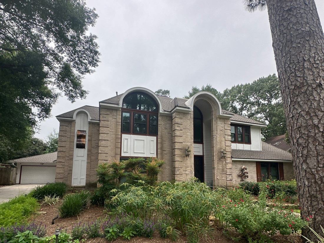 Two-story Kingwood home surrounded by tall pines after a roof replacement