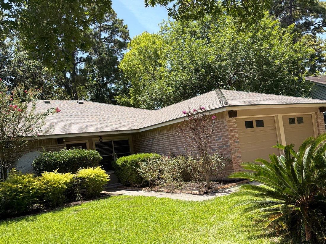 Completed roof replacement on a ranch home with mature trees in Spring