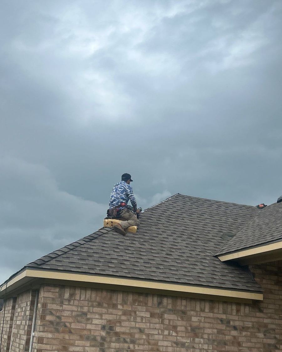 Houston Roofing crew member installing architectural shingles on a residential roof